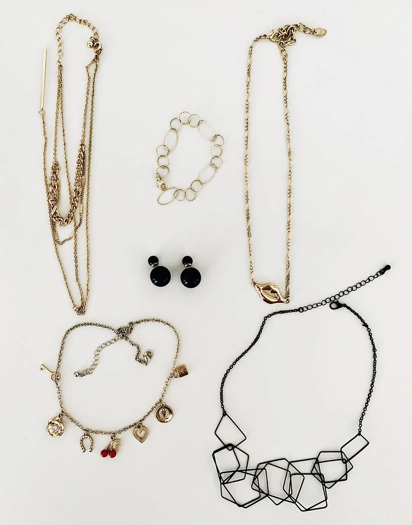 Photo of six pieces of costume jewelery on a white table, sorted out during a simplified declutter challenge.