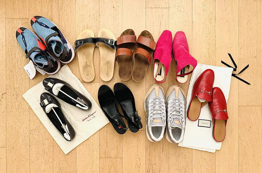 Photo of eight pairs of shoes laid out neatly on a clean oak parquet floor. The shoes include trainers from Nike, sandels, wedges, mules from Gucci, and a pair of Ferragamo ballerinas. They were all decluttered during a 30 day minimalism challenge.