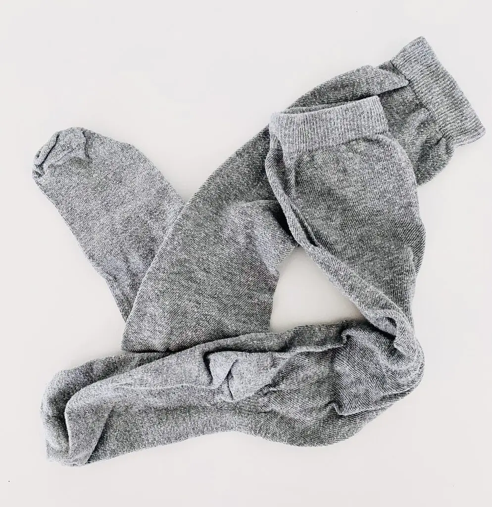 Photo of a pair of light grey socks against a white background.