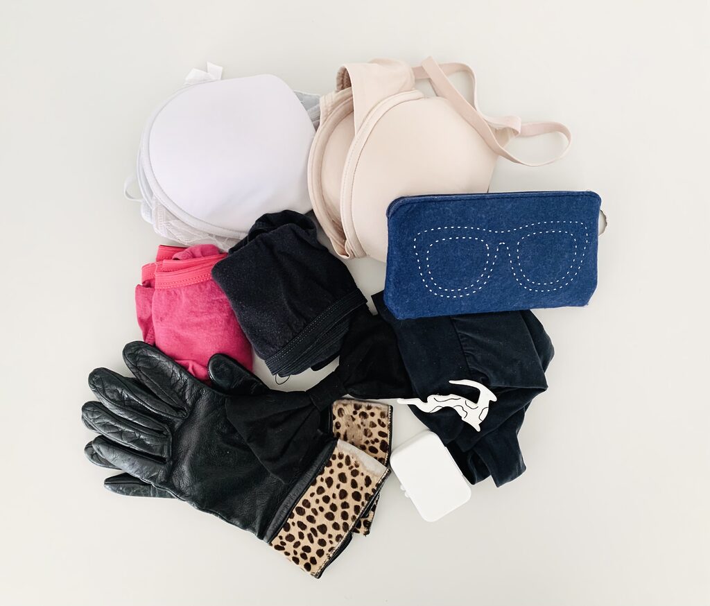 Photograph of underwear, gloves, bras and an eyeglass pouch that were decluttered from the closet during a 30 day tidyup challenge. The items are photographed from above against a white background.