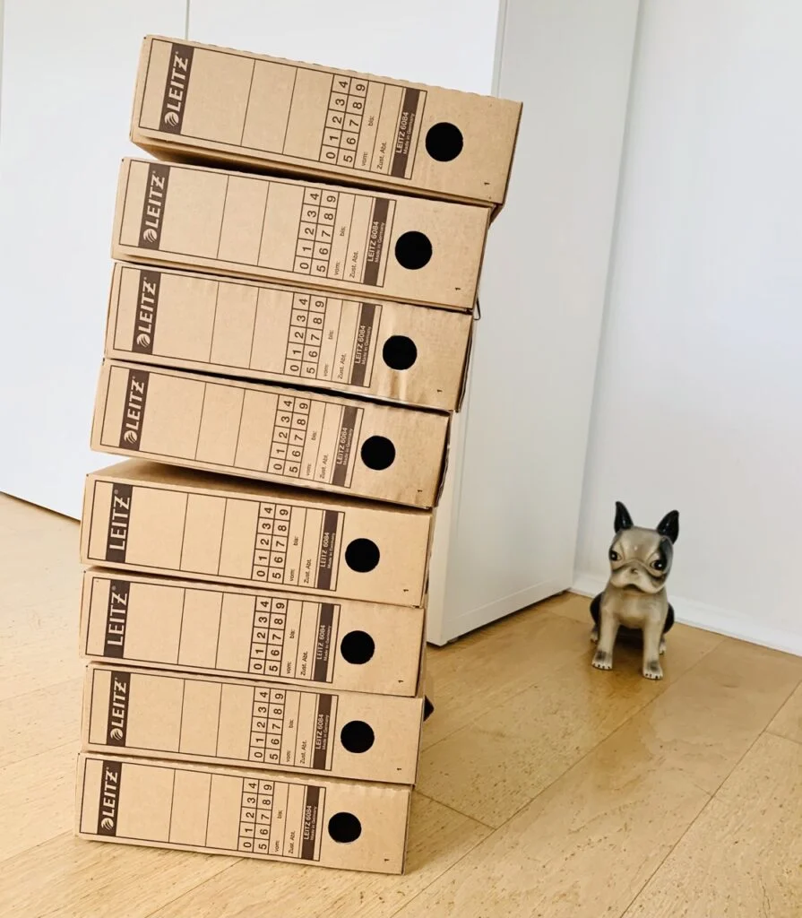 Stack of 8 brown cardboard Leitz archive boxes sorted out during a minimalist 30 day declutter challenge.