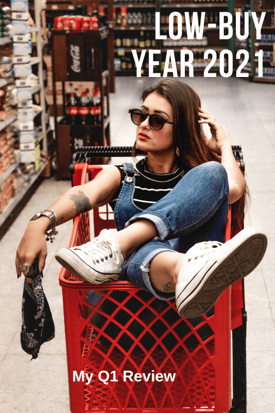 Girl in denim overalls wearing sunglasses, casually sitting in an empty supermarket shopping cart. The caption reads "Low-Buy Year 2021. My Q1 Review"