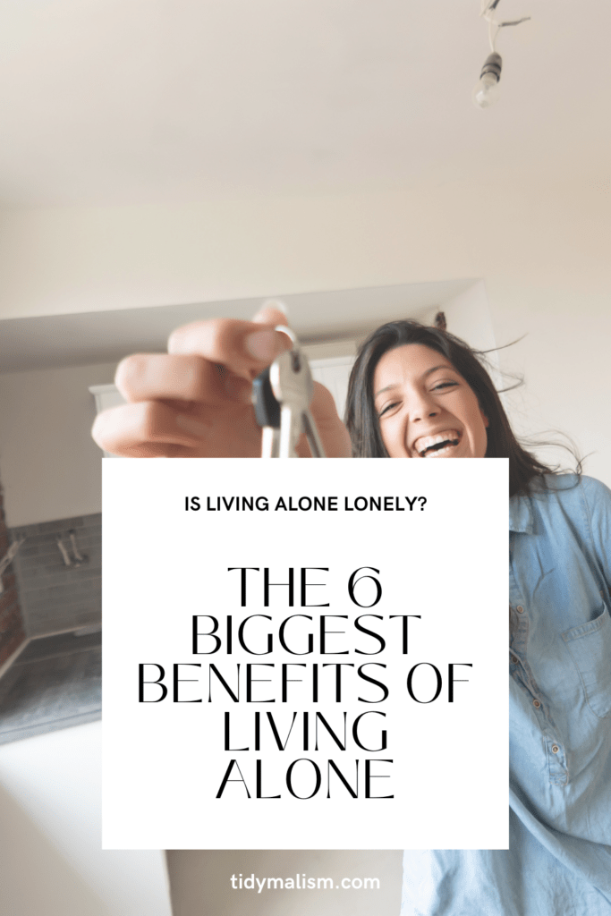 Young lady happily holding the keys to her new home and smiling. Caption reads: Is living alone lonely? The 6 biggest benefits of living alone. tidymalism.com