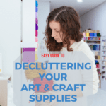 White, brunette woman with shoulder-length hair decluttering balls of yarn in the stash of hobby supplies stored in her craft room.