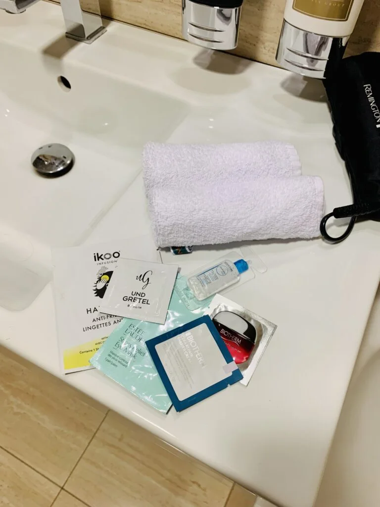 Photograph of trial-sized facial treatment products like cream, toner, eye serum, all being used on a short trip while staying at a hotel.
