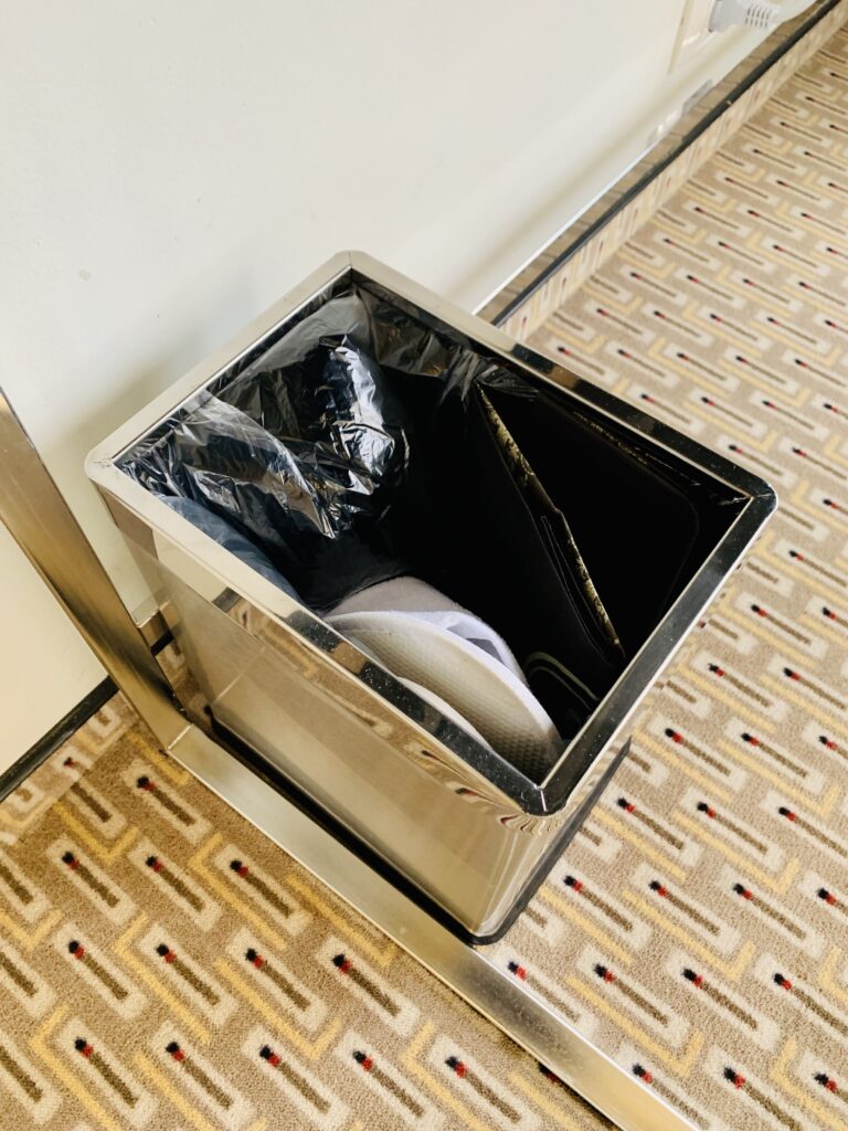 Photograph of a hotel room wastebasket. The guest has collected all their garbage before checking out and deposited it in the bin.