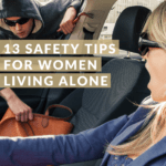 Lady in her standing car, likely at a light, shocked by a young man in sunglasses holding a crowbar, who is reaching through the window of her passenger's seat and about to steal her handbag. Caption reads 13 safety tips for women living alone.