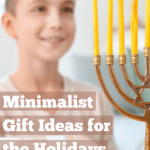 Young boy standing in front of the Hanukkah menorah with brightly lit yellow candles. There is one gift laid out for him next to the menorah and he is smiling as he gazes into the candlelight. Caption reads: minimalist gift ideas for the holidays and any time of the year.