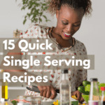 Black female millennial in a white, floral printed, short sleeved dress standing at a light-colored wood countertop chopping vegetables to prepare for cooking. The wall behind her is white and there is a large plant in the background. She has a variety of ingredients laid out before her, such as olive oil, sea salt in a mason jar, soy sauce, fresh zucchini and other green vegetables. Caption reads: 15 quick single serving recipes.