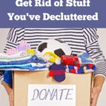 Cropped photo of a female torso in an oversized white and navy striped long-sleeved shirt, holding a box full of old toys and children's clothing. The box is labeled "Donate." Caption reads: sustainability and minimalism: the best ways to get rid of stuff you've decluttered.