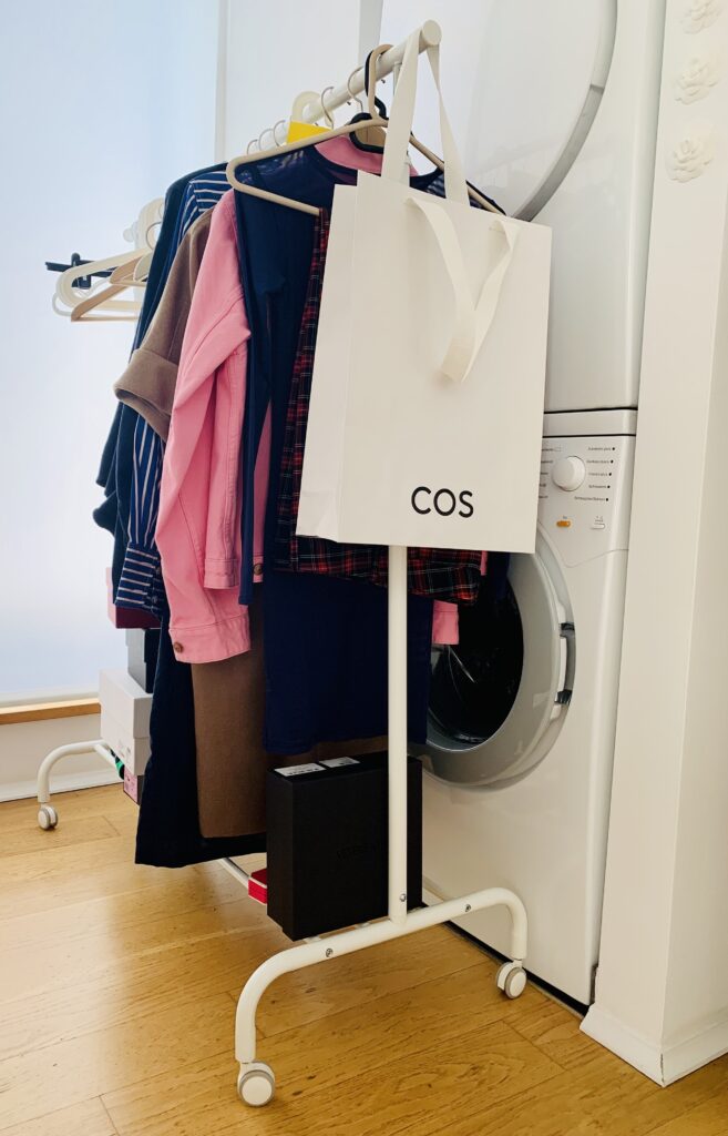 Rolling clothes rack being used in a walk in closet to declutter clothes.