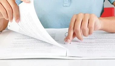 Cropped image of a white woman's hands organising an emergency documents binder.