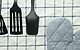 Photograph of three black silicone cooking utensils and an oven mitt on a checked tablecloth, some of the kitchen essentials for a first apartment.