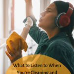 Young woman with dark hair, listening to a podcast on her red bluetooth headphones while she cleans at home. Caption reads: what to listen to when you're cleaning and decluttering? The 10 best home organization podcasts.