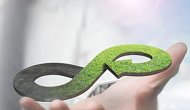Hand holding a grassy green graphical image of an infinity loop, representing the cirular economy in fashion.