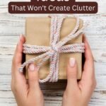 Manicured, white, female hands photographed from above, embracing a tiny parcel wrapped in environmentally friendly packaging with a twine ribbon.