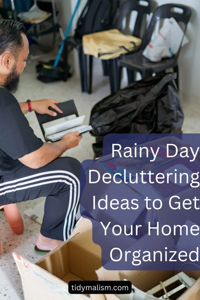 Young bearded man of color wearing Adidas jogging pants and sorting through boxes and bags of clutter. Caption reads rainy day decluttering ideas to get your home organized.
