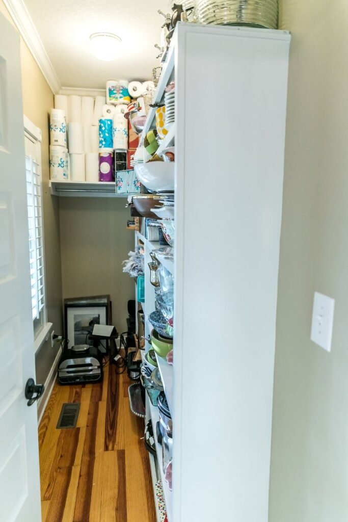 A narrow storage room with a shelving unit along the right-hand wall.
