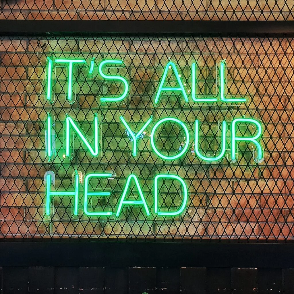 Green neon sign of a typical toxic positivity message: "It's all in your head." Photo by Miguel Luis.