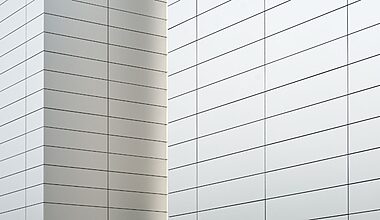 Clean, minimalist architectural photo of white, tiled walls with light grey grout.