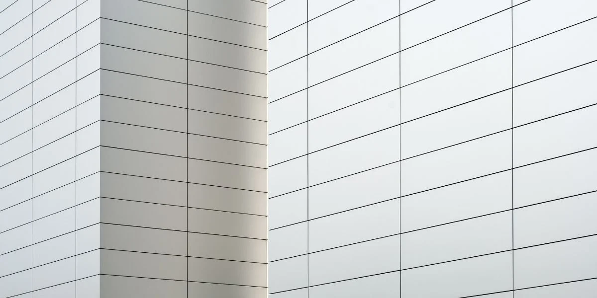 Clean, minimalist architectural photo of white, tiled walls with light grey grout.