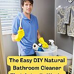 Thirty-something white guy standing near the toilet of his bathroom, wearing rubber gloves and holding up a scrub brush in his right hand. In his left hand he's carrying a caddy of cleaning supplies including a DIY natural shower cleaner.