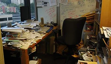 Photo of a very messy home office with tonnes of paperwork, CD-Roms, catalogues and books piled up everywhere.