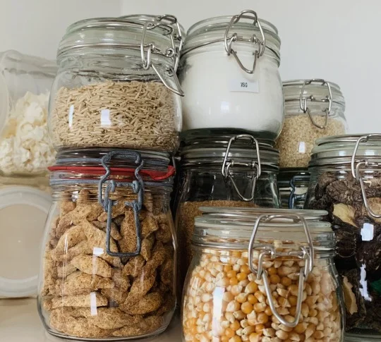 mason jars for food storage Image shows close up of clean mason jars holding dried staples such as rice, soy puffs, popcorn, dried mushrooms, coconut, MSG.