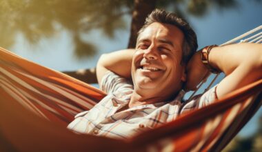 A middle-aged man enjoying some unproductive time, relaxing in the hammock outside.