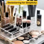 Assortment of cosmetics and makeup brushers organized in clear acrylic trays.